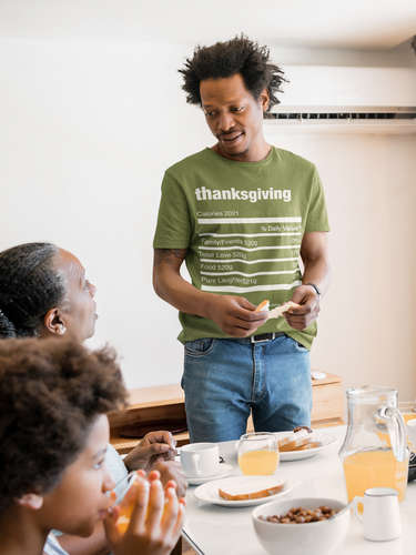 man standing at dinner table in olive color t-shirt with Thanksgiving ingredients of family/friend, love. 333 Explosion logo on left sleeve. T-shirt colors also available autumn, brown